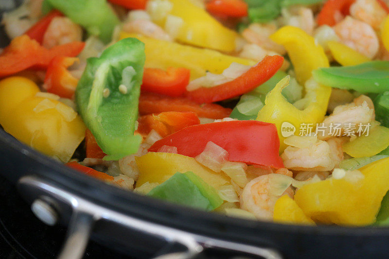 健康饮食食品的形象，东方大虾海鲜炒冻大虾/虾，切碎的洋葱丁，交通灯辣椒辣椒蔬菜，红的，黄的，绿的切片，炒晚餐的饭菜被煮在大的不干胶煎锅